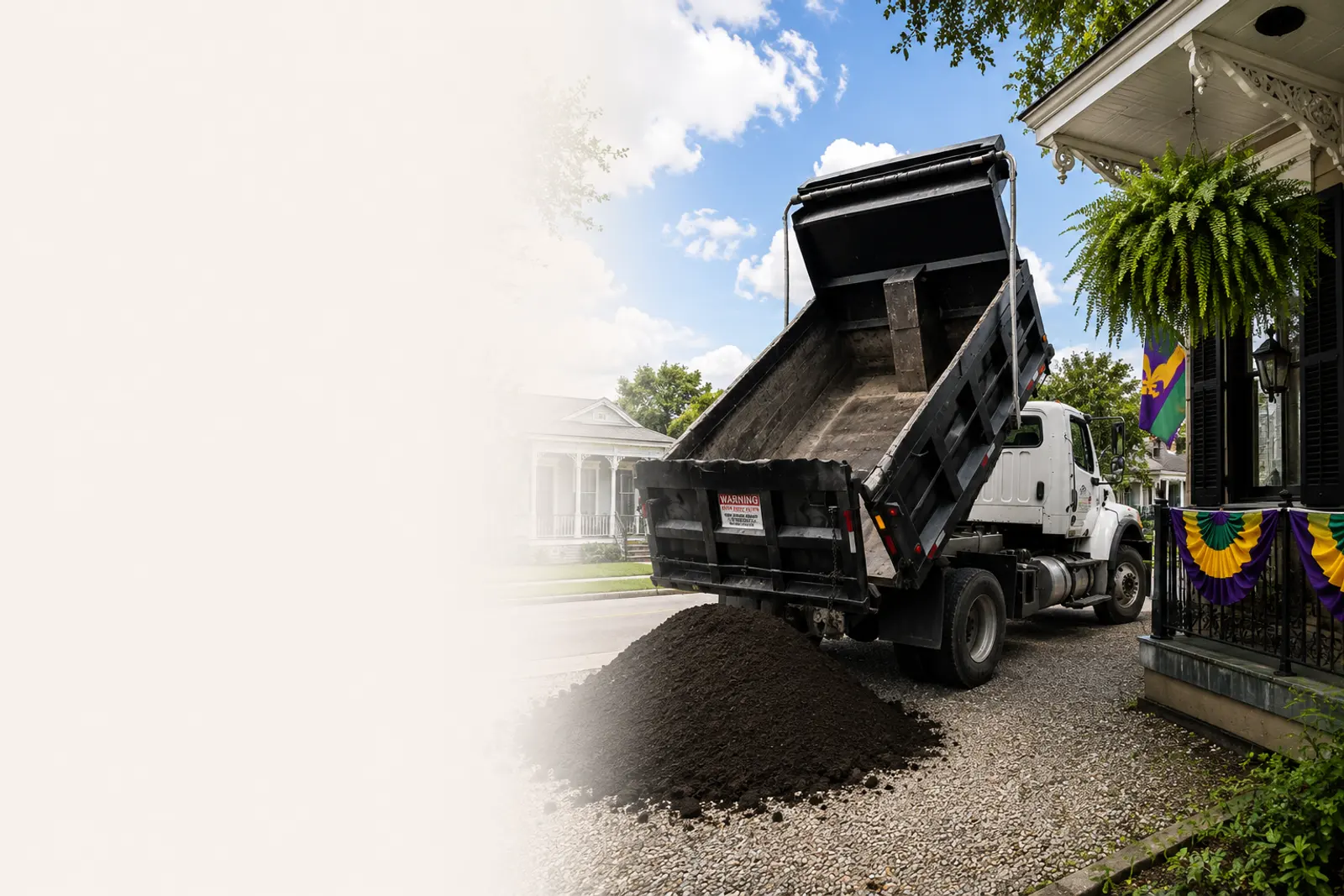 A Hello Gravel dump truck delivering a load of gravel to a New Orleans driveway